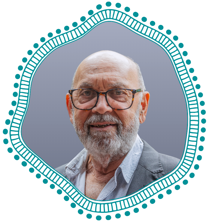 Portrait of an older man with glasses and a gray beard, wearing a light shirt and blazer, posed against a muted background with a teal decorative frame.